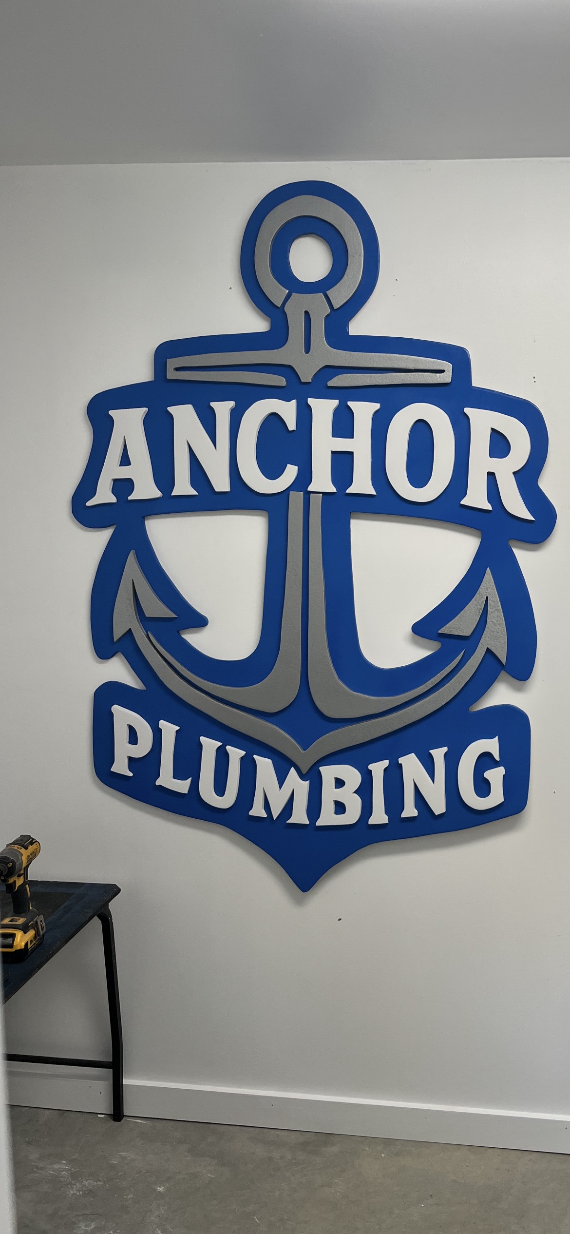 Plumbing company sign hand-cut and layered, hung in the shop